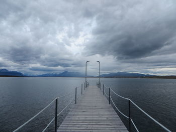 Pier on lake against cloudy sky