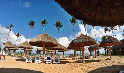 Lounge chairs and umbrellas on beach against blue sky