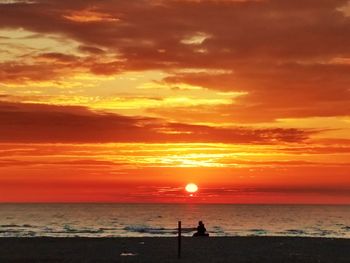 Silhouette people at beach against sky during sunset