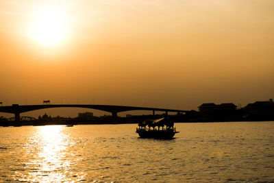 Silhouette bridge over river against sky during sunset