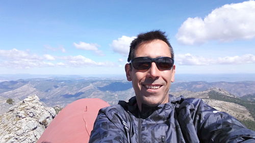 Portrait of smiling man on mountain against sky