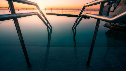 Swimming pool by sea against sky during sunset
