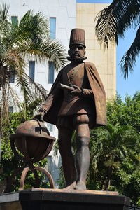 Low angle view of statue against trees and building