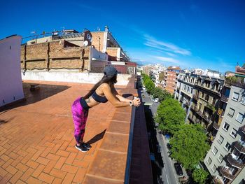 Full length of woman standing on building terrace in city during summer