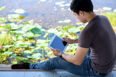 Side view of man using mobile phone outdoors