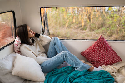 Young woman using phone while sitting on sofa at home