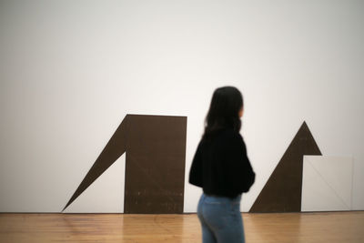 Rear view of woman standing against wall