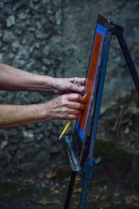 Cropped image of person painting on canvas outdoors