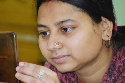 Close-up portrait of smiling girl using smart phone