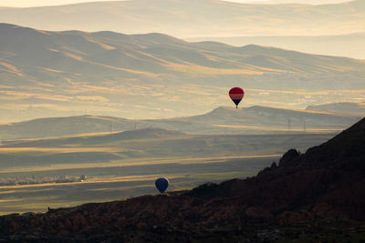 Hot air balloon flying over mountains against sky
