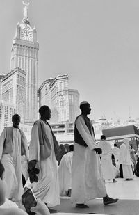 Rear view of people walking in front of building against clear sky