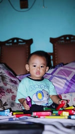 Portrait of cute baby girl sitting on bed at home