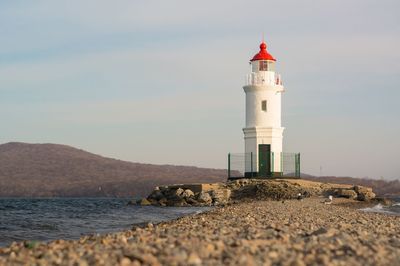 Lighthouse by sea against sky