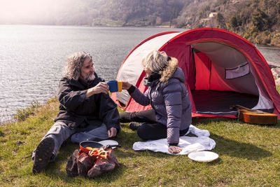 People sitting on tent by lake