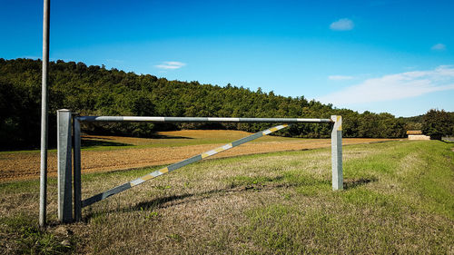 Fence on field against blue sky