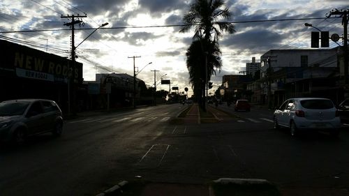 Cars on street against cloudy sky