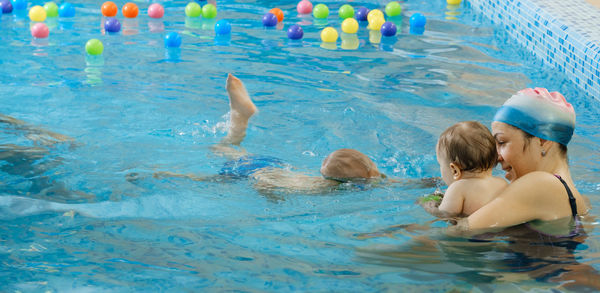 Toddler child learning to swim in indoor swimming pool with teacher. and general physical activity