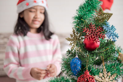 Close-up of christmas tree with girl in background