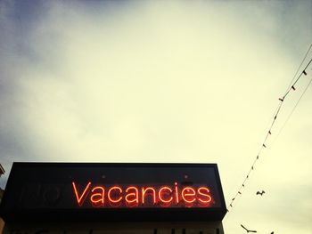 Low angle view of sign board against sky