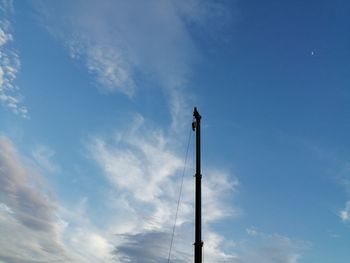 Low angle view of man working against blue sky