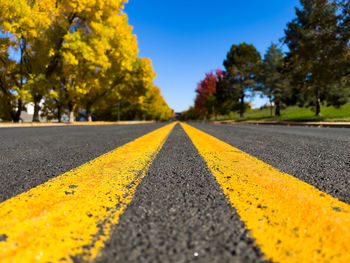 Closeup of double yellow lane lines on road with diminishing perspective and shallow depth of field