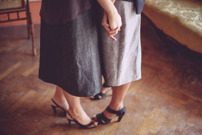 Low section of lesbian couple standing on wooden floor