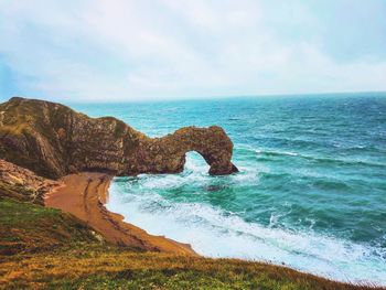 Scenic view of rock formation in sea against sky