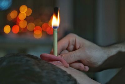 Close-up of hand holding burning paper in man ear