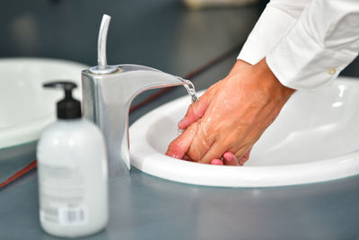 Cropped image of man washing hands in sink