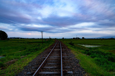 Railroad tracks on field against sky