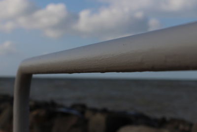 Close-up of metal chain on shore against sky