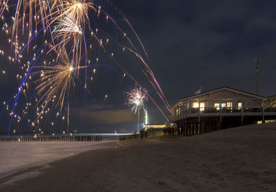 Firework display at beach against sky at night