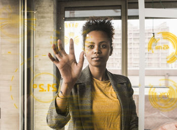 Young woman touching glass wall with data in office