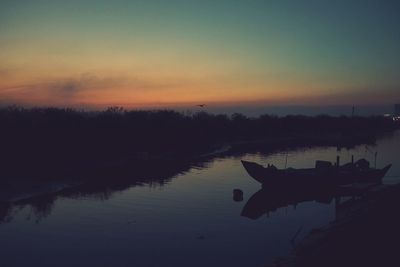 Boat on river against sky during sunset