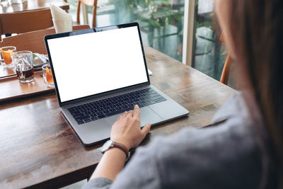 Midsection of woman using laptop at cafe