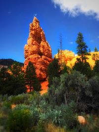 Low angle view of trees on mountain against blue sky