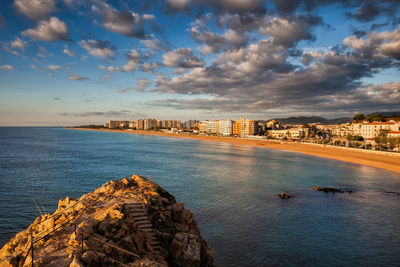 Panoramic view of sea and buildings against sky during sunset