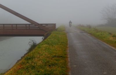Man walking on road against sky during foggy weather