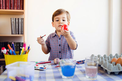 Boy painting easter egg at home