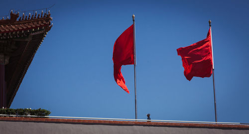 Low angle view of red flags at forbidden city against clear blue sky