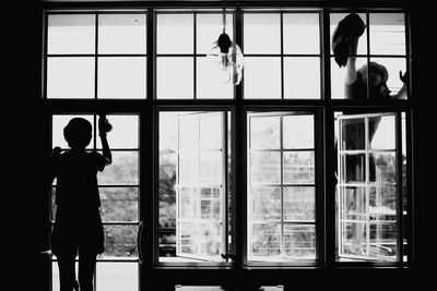 Rear view of silhouette women cleaning glass window