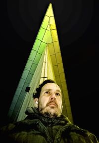 Portrait of young man standing against illuminated wall