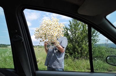 Man holding flowers while standing outdoors