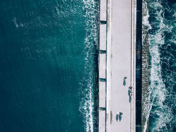 High angle view of people walking on pier over sea during sunny day