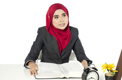 Portrait of a young woman sitting against white background