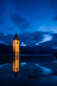 Scenic view of lake by building against sky at dusk