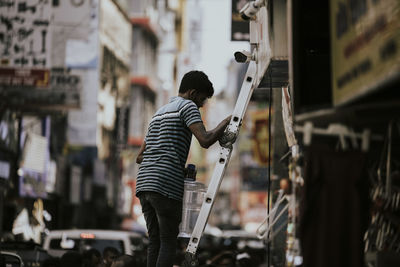 Rear view of boy standing in city