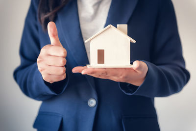 Midsection of man holding paper while standing against building