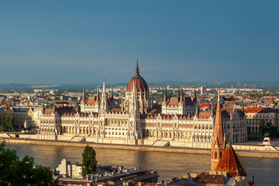 Bridge over river by buildings in city against sky