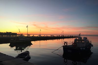 Boats moored at harbor against sky during sunset